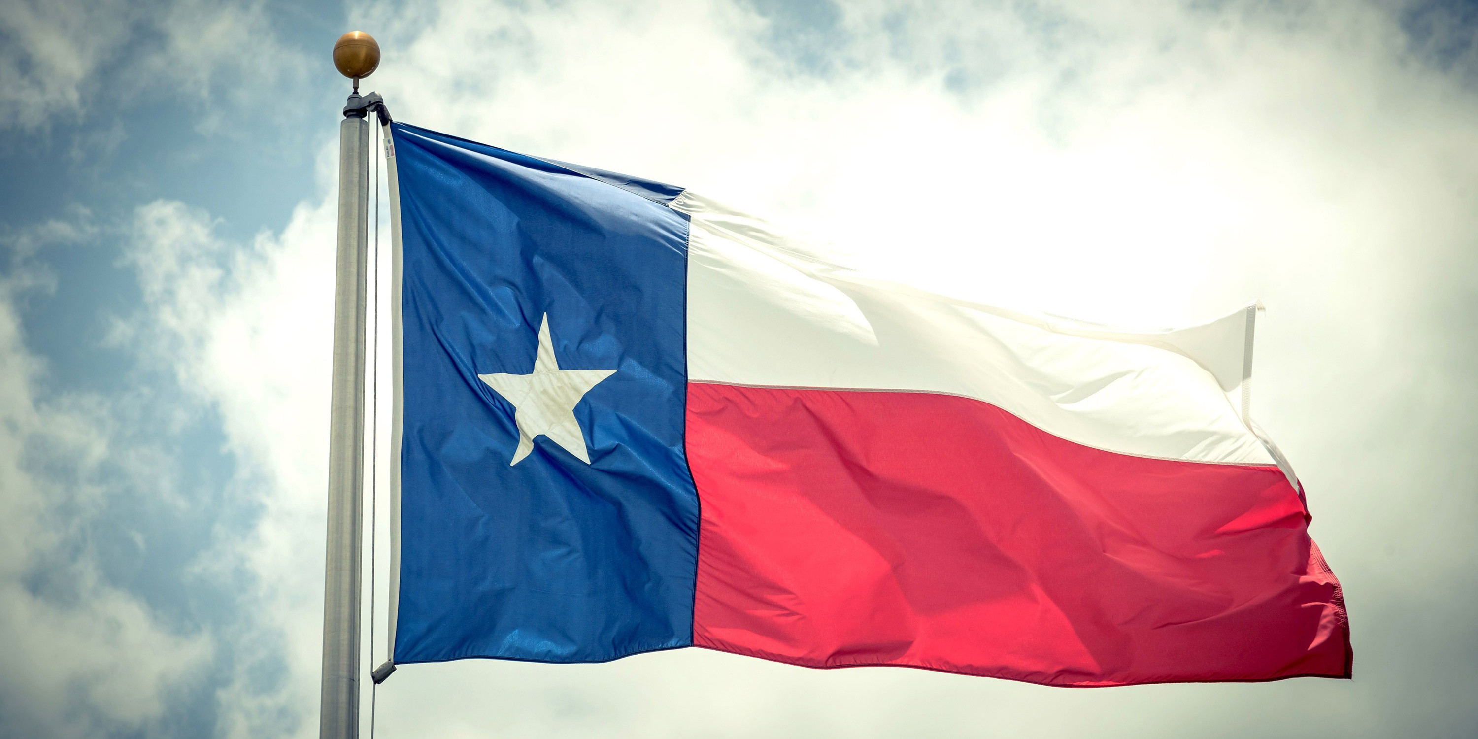 Texas flag against a background of clouds